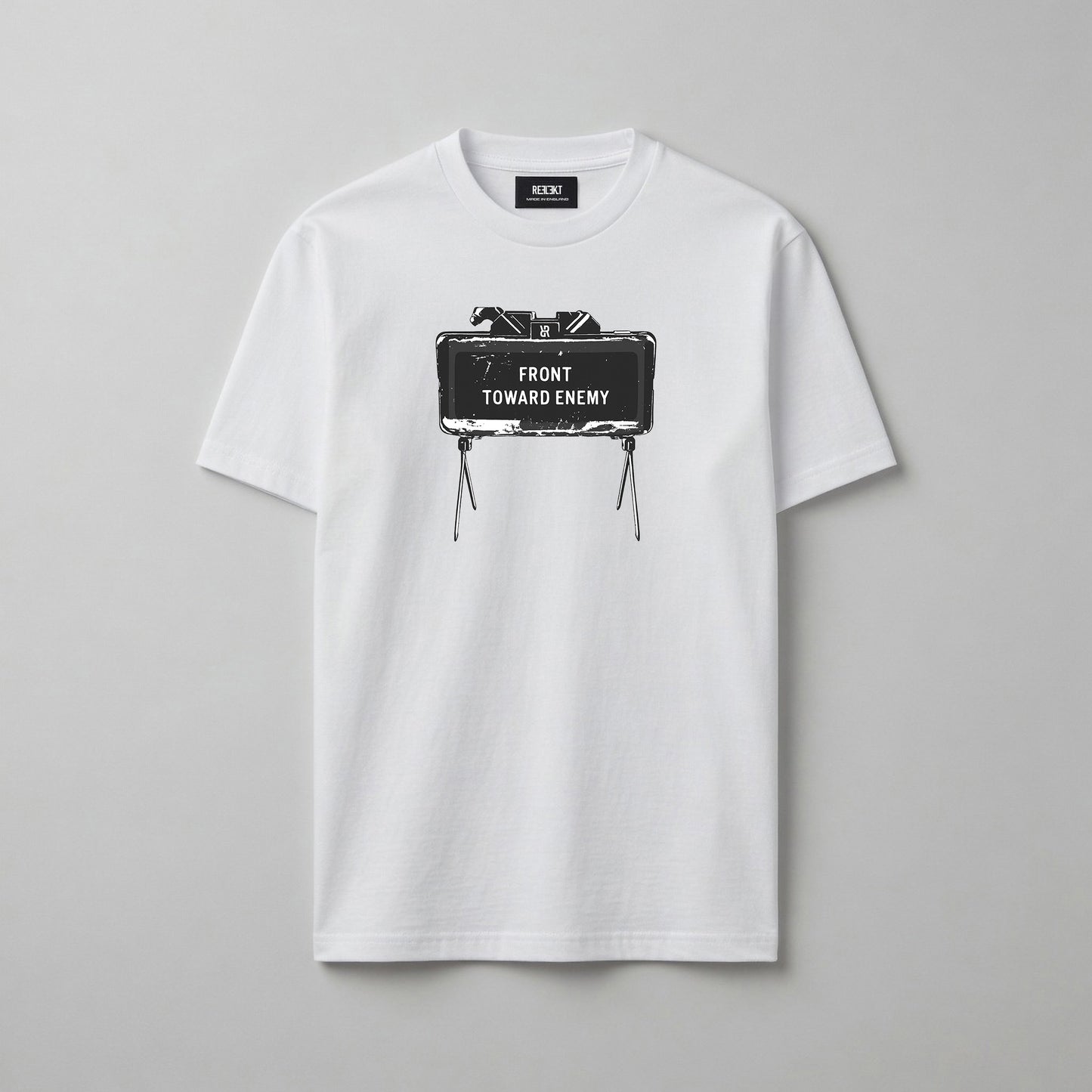 A white short-sleeve crewneck t-shirt with a graphic print of a Claymore Mine that reads 'FRONT TOWARD ENEMY' on the chest, displayed flat against a neutral grey background.