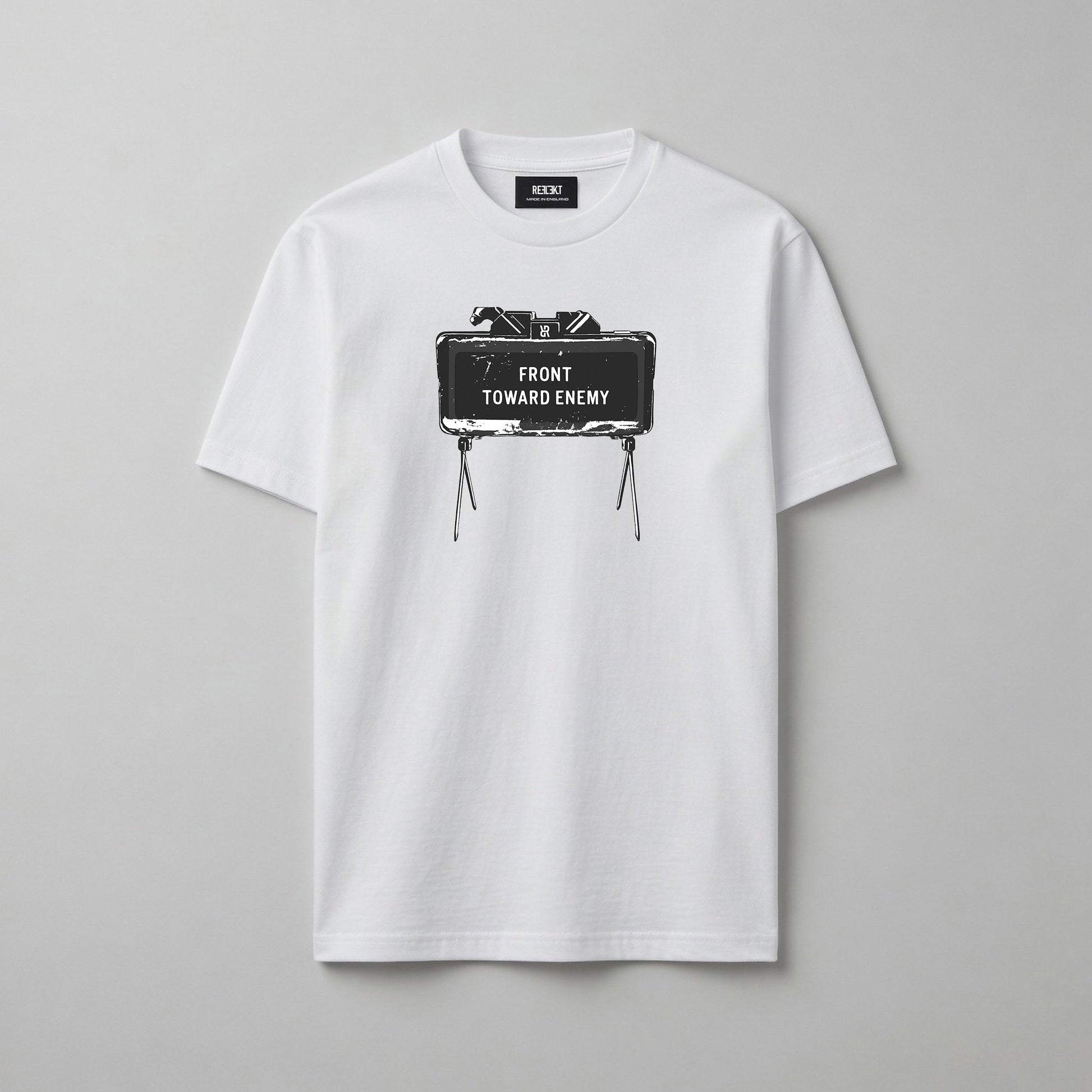A white short-sleeve crewneck t-shirt with a graphic print of a Claymore Mine that reads 'FRONT TOWARD ENEMY' on the chest, displayed flat against a neutral grey background.
