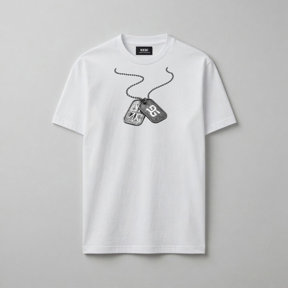 A white short-sleeve crewneck t-shirt featuring a black and grey graphic of military dog tags on a chain across the chest, displayed on a neutral grey background.