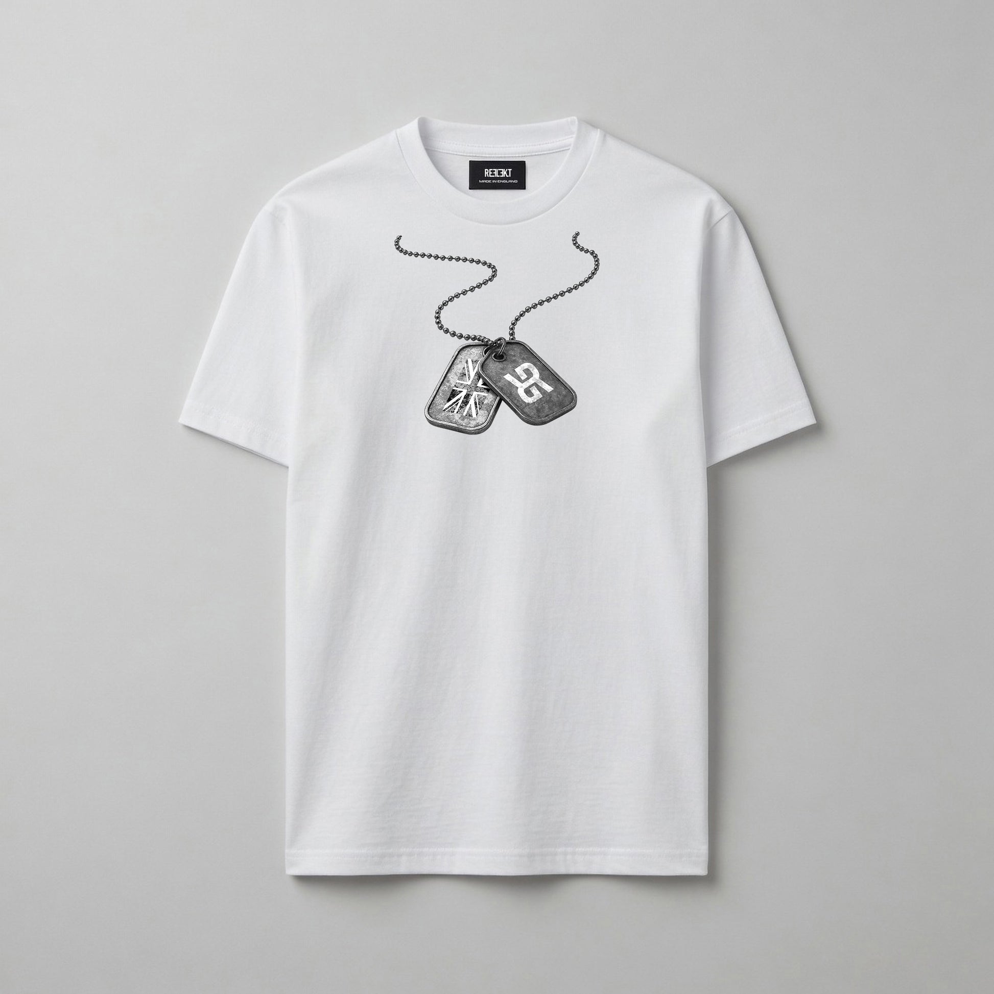 A white short-sleeve crewneck t-shirt featuring a black and grey graphic of military dog tags on a chain across the chest, displayed on a neutral grey background.