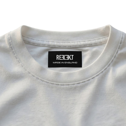 Close-up of a white shirt with a black REFLEKT label on a light gray background