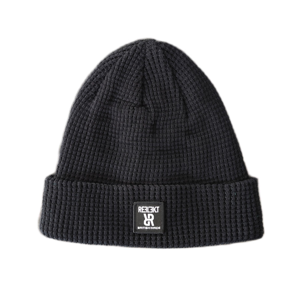 Black REFLEKT waffle‑knit beanie with front woven British‑made label.